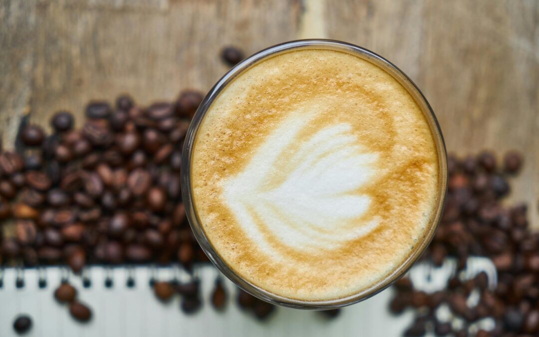Freshly brewed coffee sitting on scattered roasted coffee beans